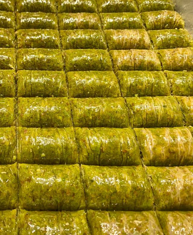 Reihen von leuchtend grüner Fıstık Sarma im Blech